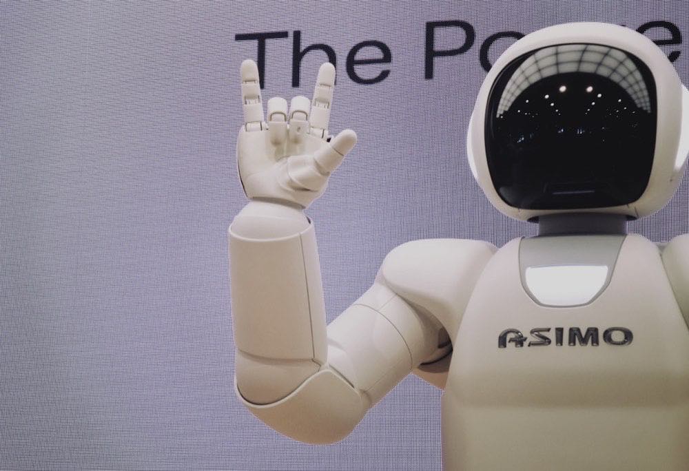 Industrial humanoid robot working alongside human staff on a warehouse production floor